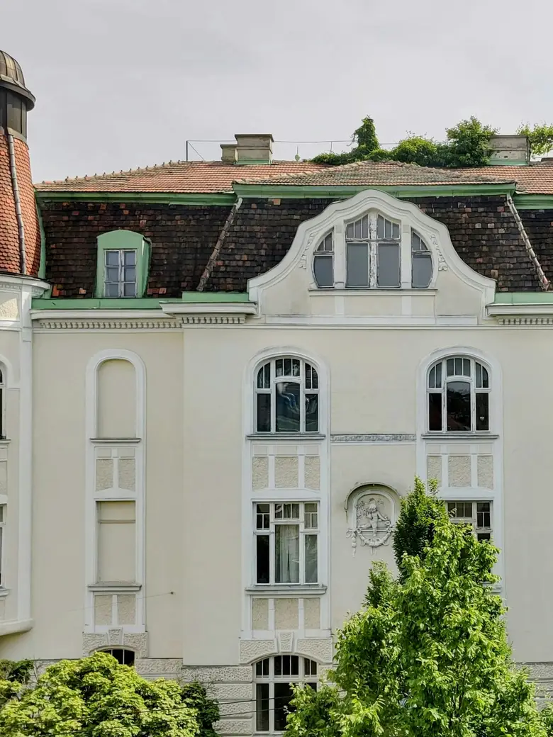 Weiße Jugendstilvilla mit Turm hinter Bäumen